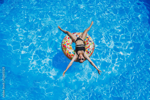Beautiful woman in sunglasses in the pool floats on an inflatable swimming ring in a black swimsuit  summer photo  swimming photography  summer woman photos