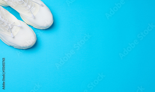 White textile sneakers on a blue background, top view