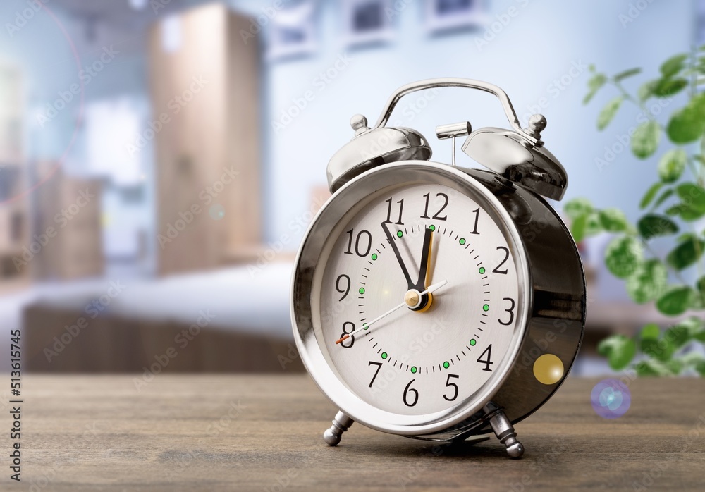 Alarm clock morning wake-up time on bedside table by background Alarm clock morning wake-up time on bedside table by background