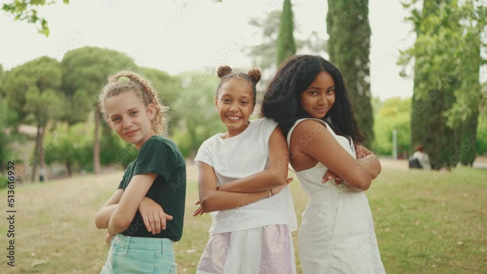Smiling three girls friends pre-teenage cross their arms in dance move in the park Smiling three girls friends pre-teenage cross their arms in dance move in the park