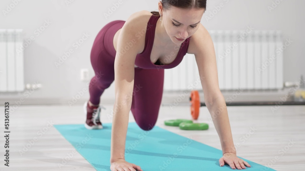 a beautiful and slender woman in a burgundy tracksuit exercises on a mat a beautiful and slender woman in a burgundy tracksuit exercises on a mat