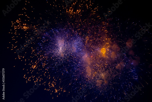 Purple and orange sparks of fireworks on the background of the night sky. High quality photo