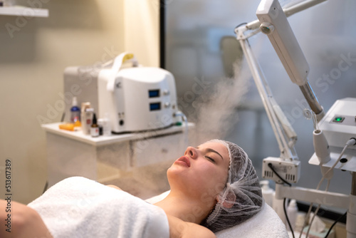 Beautiful woman on ozone therapy with facial steamer in beauty salon. photo