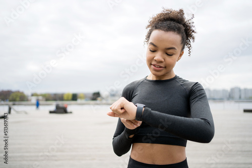 Uses a fitness watch on his arm. Woman fitness training on the street, active exercises in a sports uniform
