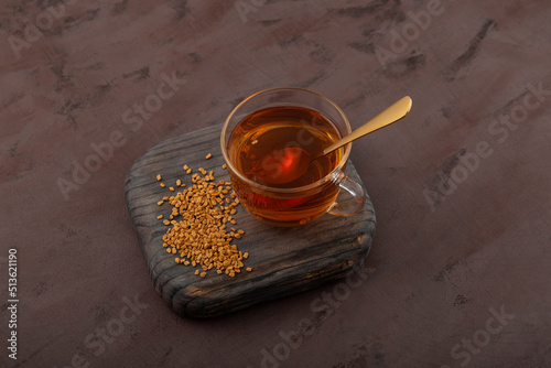 Fenugreek tea on brown background, top view. Healthy drink of plant Trigonella foenum-graecum