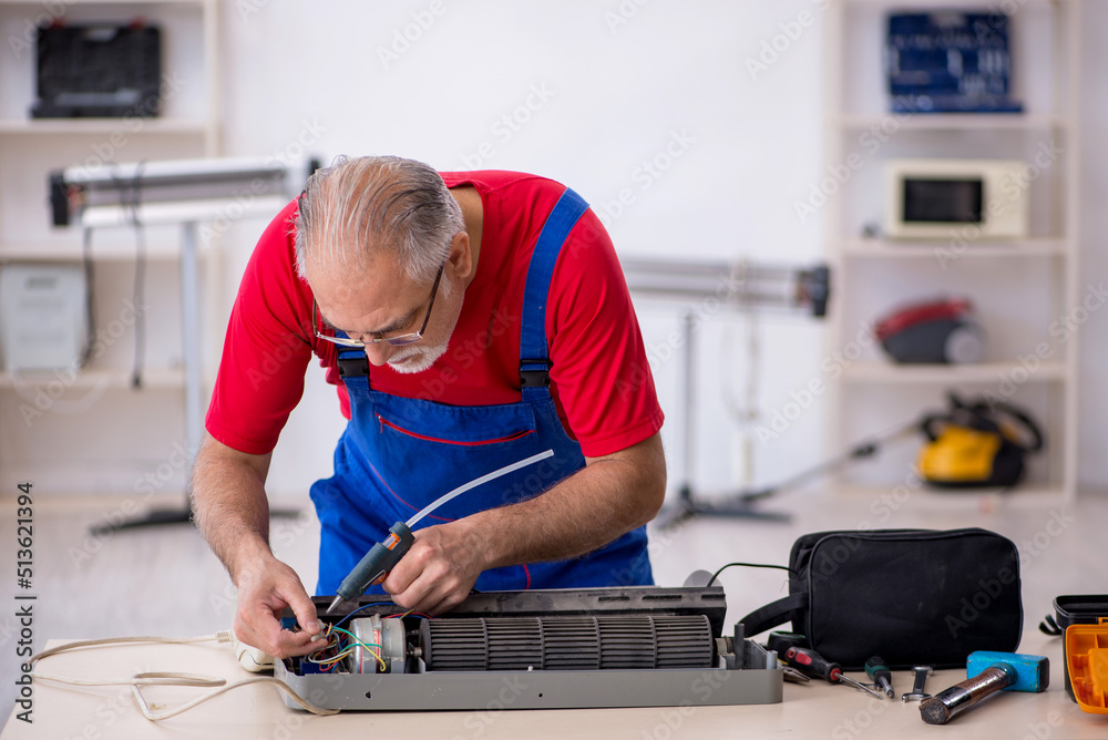 Old repairman repairing air-conditioner at workshop Old repairman repairing air-conditioner at workshop