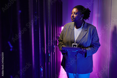 Fototapet Portrait of female system administrator inspecting data network in server room l