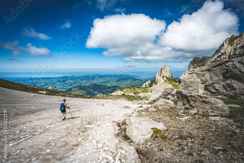Hiker walking accross a snow field with the view on Appenzell and the lake constance