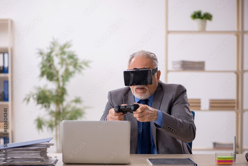 Old male employee enjoying virtual glasses at workplace