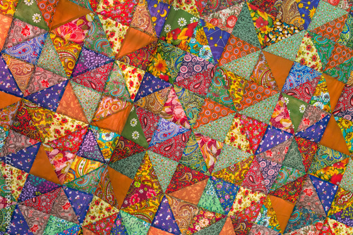 Quilt, colorful fabric texture with flowers and geometric patterns. Floral red orange green blue yellow textile background