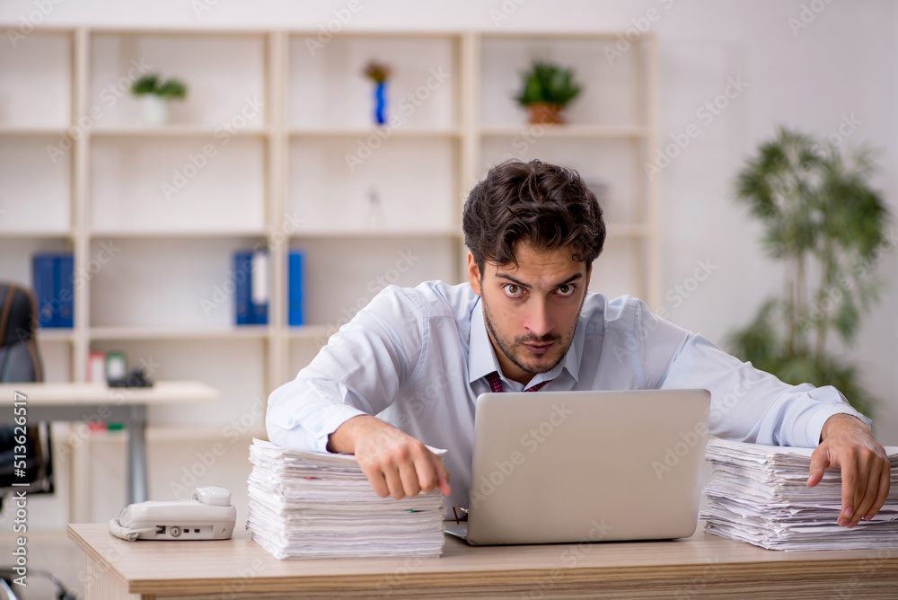 Young male employee and too much work in the office Young male employee and too much work in the office