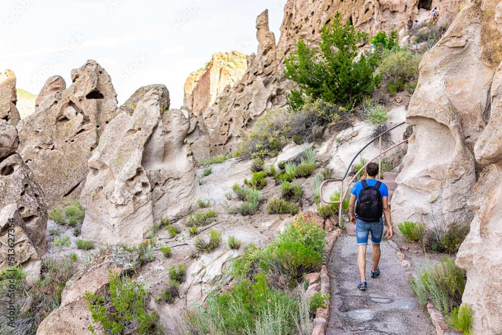 Fototapeta premium Man hiking walking on Main Loop trail footpath in Bandelier National Monument in New Mexico, USA during summer with cliff cave dwellings used by native people