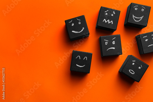 Many cubes with different emotions on orange background, flat lay and space for text. Emotional management photo