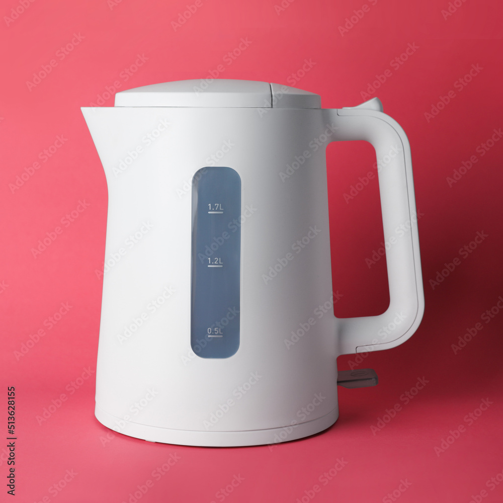 New modern electric kettle on red background New modern electric kettle on red background