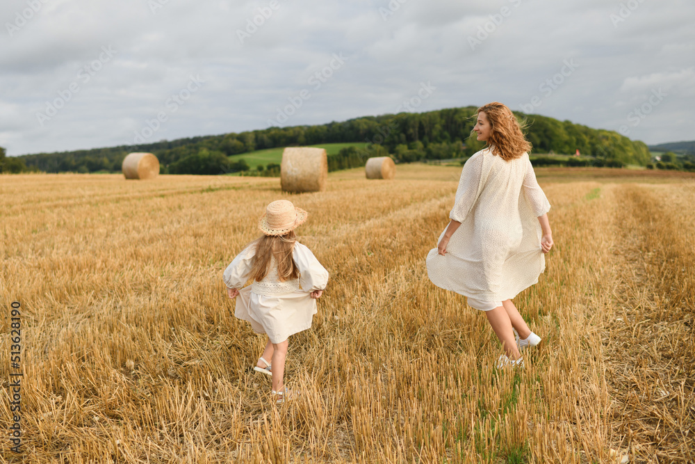 Mother plays with daughter in a field with wheat Mother plays with daughter in a field with wheat