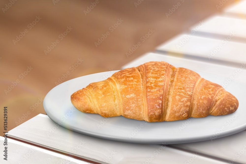 Croissant on a white plate, freshly baked.