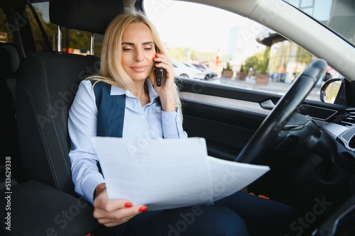 Serious business woman in the car examines important documents. © Serhii