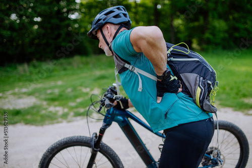 Canvastavla Active senior man in sportswear suffiering from pain in his back after cycling, in park in summer