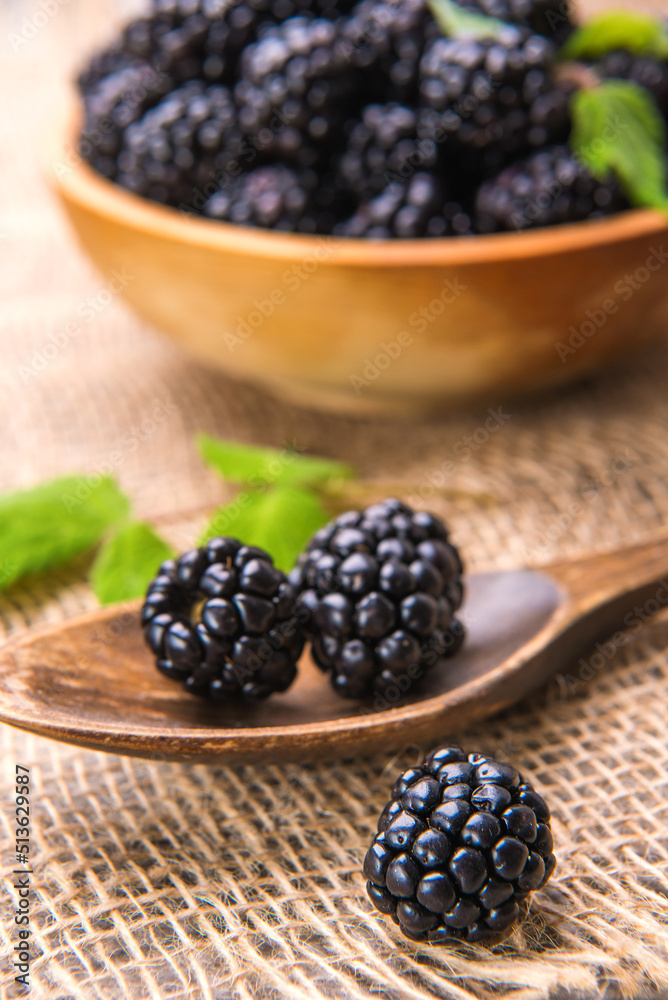 Blackberry close-up on the background of a wooden spoon with blackberries. Blackberry close-up on the background of a wooden spoon with blackberries.