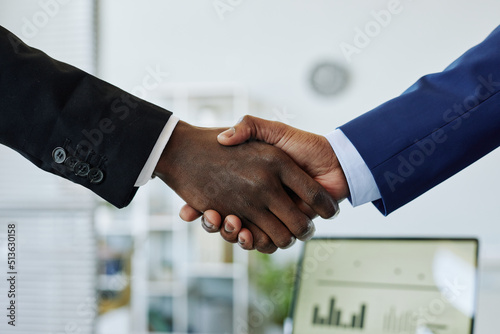 Close up of two business people shaking hands after successful partnership negotiation in office