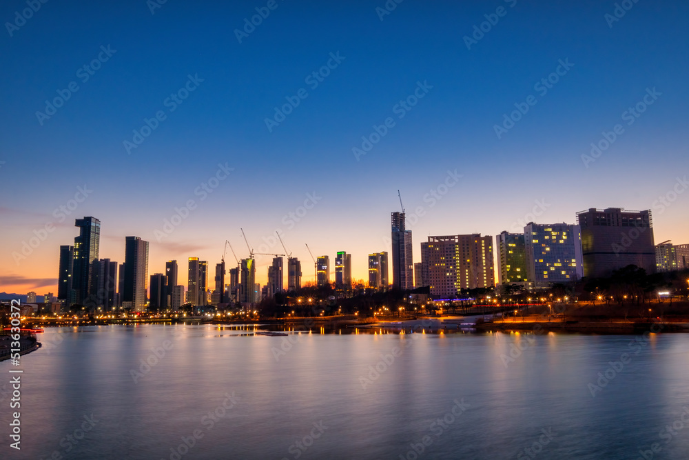 Naklejka premium Scenic view of lake and city scape against sky during sunset