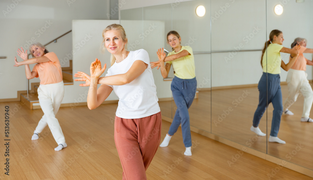 Young girl with her mother and grandmother dancing aerobics at lesson in the modern dance class