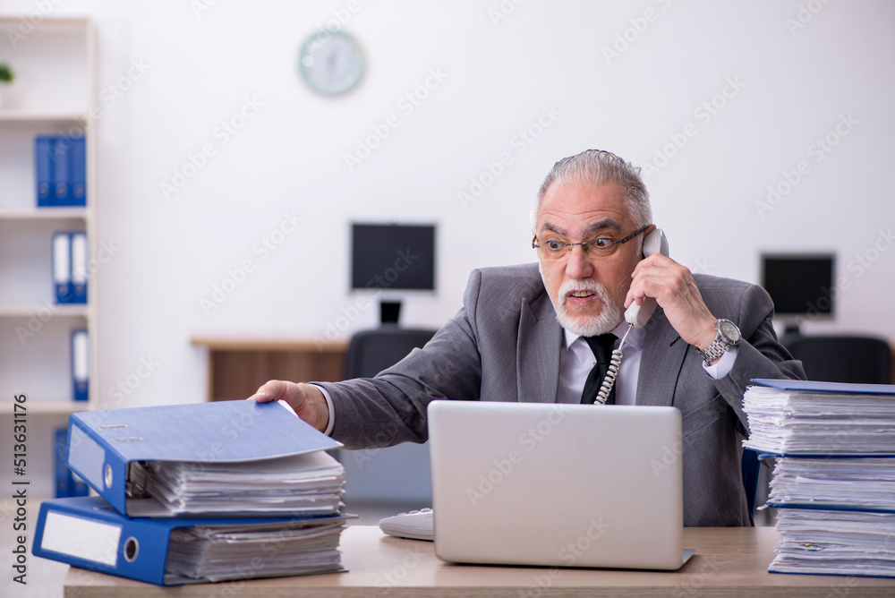 Old male employee unhappy with excessive work in the office Old male employee unhappy with excessive work in the office