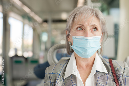 European elderly woman sitting inside tram and waiting for next stop.