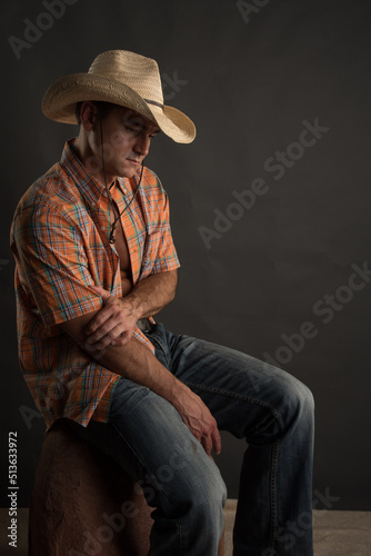 The attractive cowboy man is posing in a studio for the photo. photo