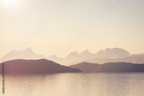 siluetas de cerros y montañas en la distancia en lago brumoso con colores de medio día magentas 