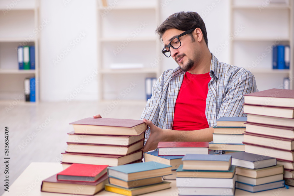 Young male student and too many books in the classroom Young male student and too many books in the classroom