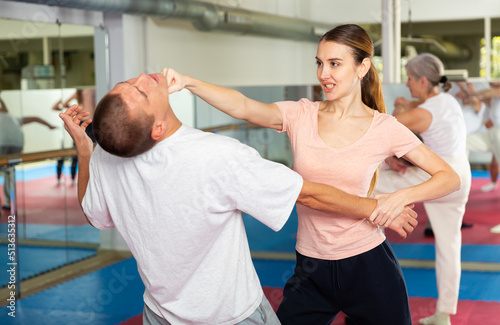 Basic self-defense techniques for women. Girl blocking hand of male opponent and launching strike in chin with fist during workout at gym © JackF