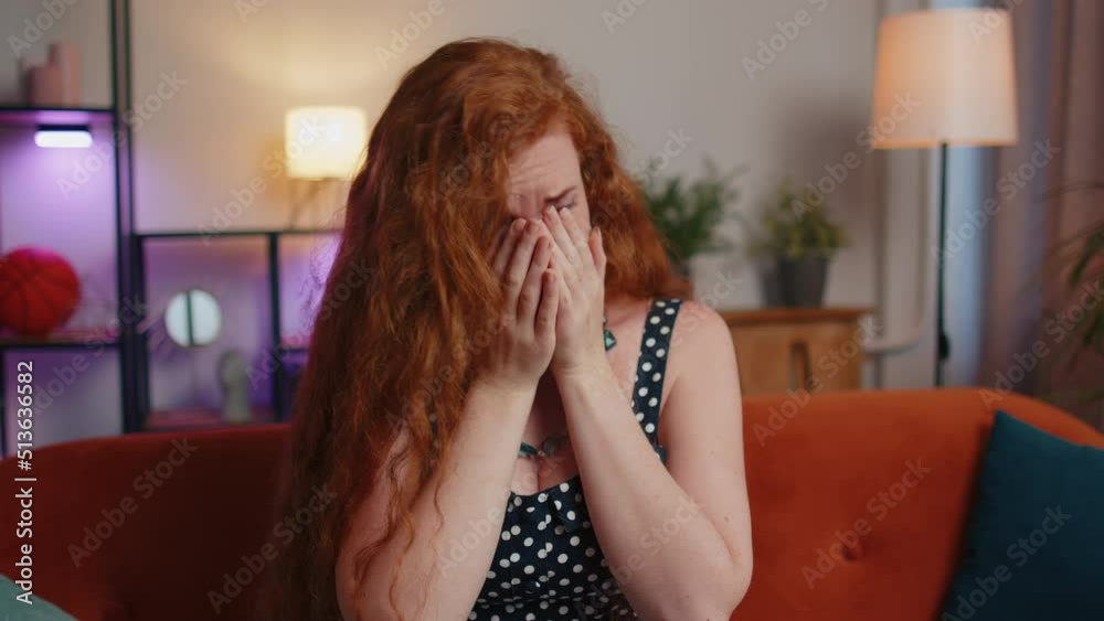 Upset disappointed redhead freckles girl wipes tears and cries from despair, being sad because of unfair situation, unrequited love. Problem, break up, depressed feeling bad annoyed, burnout at home