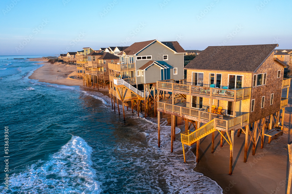 Aerial view of homes right on the shoreline in the ocean during high tide in Buxton North Carolina Outer Banks - obrazy, fototapety, plakaty 