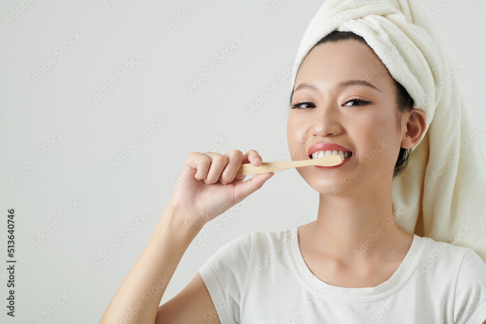 Portrait of joyful young Vietnamese woman with towel on her head brushing teeth Portrait of joyful young Vietnamese woman with towel on her head brushing teeth