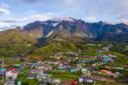 Beautiful aerial view of rocky mountain range Mount Kinabalu with village and green vegetation at foreground.