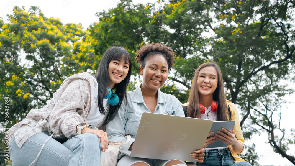 Diversity woman group happy friends searching media content online using laptop sitting in the park. looking online lessons on laptop with her friends at park. Prepare for college university concept. Diversity woman group happy friends searching media content online using laptop sitting in the park. looking online lessons on laptop with her friends at park. Prepare for college university concept.