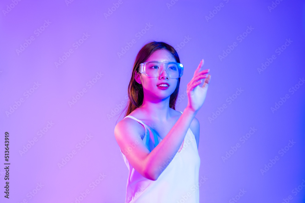 Asian woman long hair style in white tank top wearing vr glasses posing hand touching on purple background.
