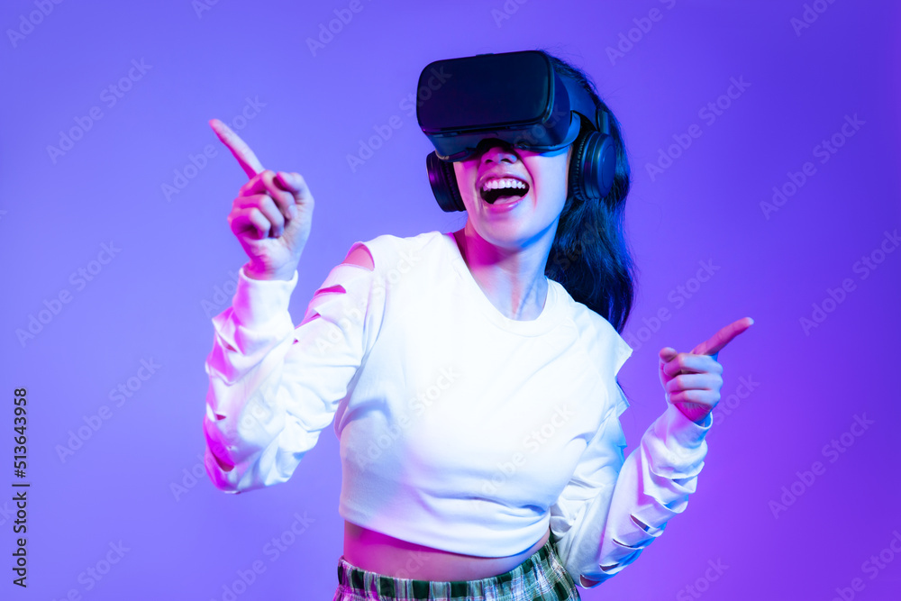 Metaverse concept, young asian girl in white fashion sweatshirt wearing vr headset playing touching online game purple background.
Metaverse concept, young asian girl in white fashion sweatshirt wearing vr headset playing touching online game purple background.