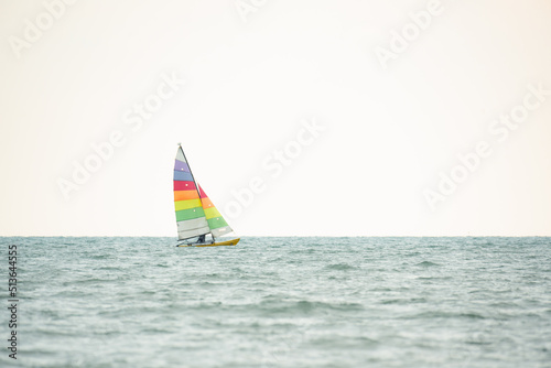 Sailboat in the sea on white sky background.Luxury summer adventure and active vacation in the ocean.Sport sailboat sailing through a silver sea in a sunny day.