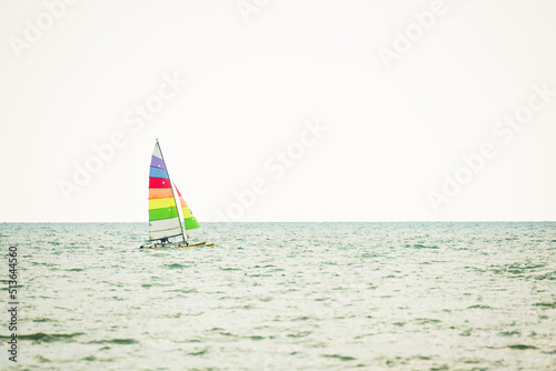 Sailboat in the sea on white sky background.Luxury summer adventure and active vacation in the ocean.Sport sailboat sailing through a silver sea in a sunny day.