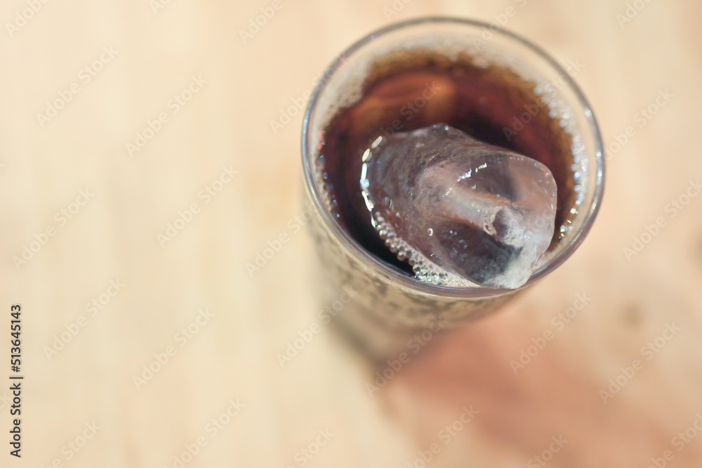 Close up cola and ices in the glass on wooden table background.Top view cool ice soft drink liquid fresh food.Lifestyle and people unhealthy drinking concept. Close up cola and ices in the glass on wooden table background.Top view cool ice soft drink liquid fresh food.Lifestyle and people unhealthy drinking concept.
