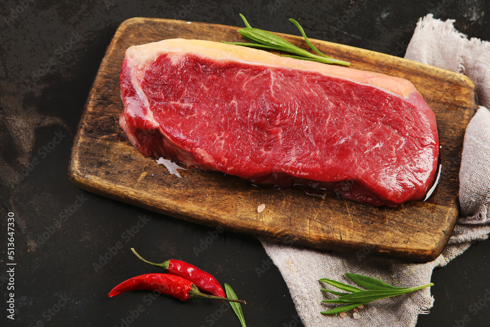 Raw striploin beef steak dark background.