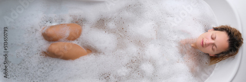 A young woman lies in a soapy foam bath  top view