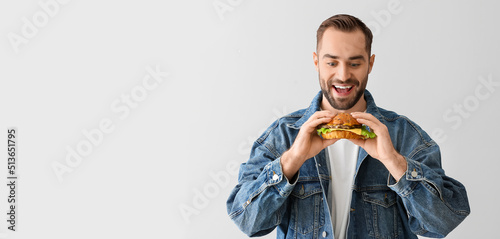 Young man eating tasty burg...