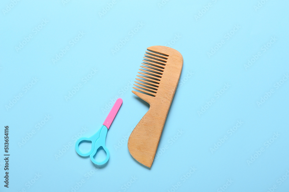 Wooden hair comb and scissors for baby on blue background Wooden hair comb and scissors for baby on blue background