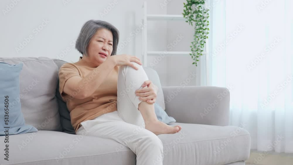 Older women are hurting their legs. She felt a lot of pain. The back of the leg hit the table. woman sitting on the sofa at home Older women are hurting their legs. She felt a lot of pain. The back of the leg hit the table. woman sitting on the sofa at home