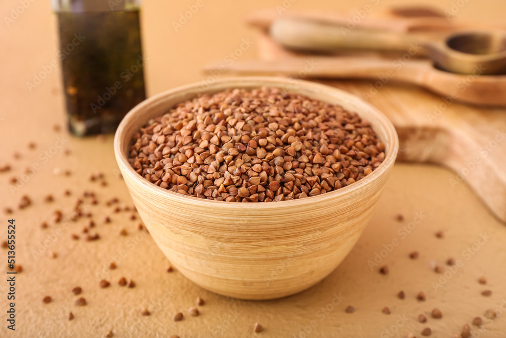 Wooden bowl with buckwheat grains on color table Wooden bowl with buckwheat grains on color table