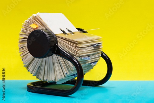 Rolodex file organizer on office desk, side view with colorful background, retro communication address cards.