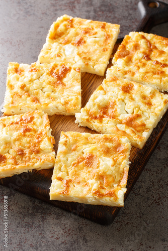 Alevropita Greek Thin Batter Feta Pie close-up on a wooden board on the table. Vertical photo